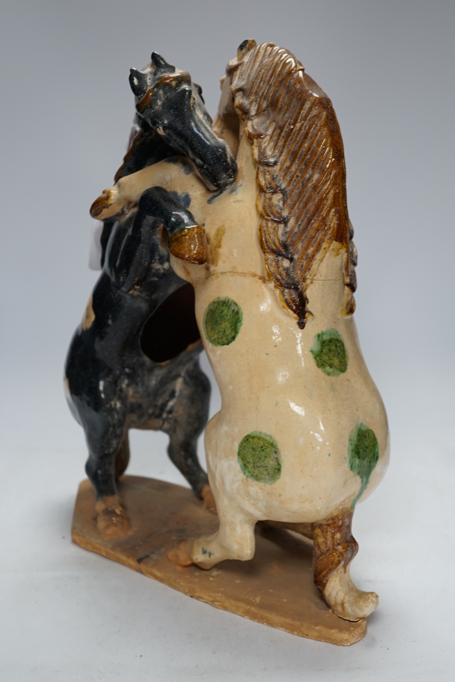 A Chinese sancai glazed group of fighting horses, Tang or later, 39cm high